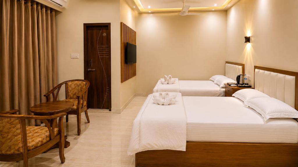 a hotel room with two beds and a desk at Hotel Grand Darbar in Barisāl