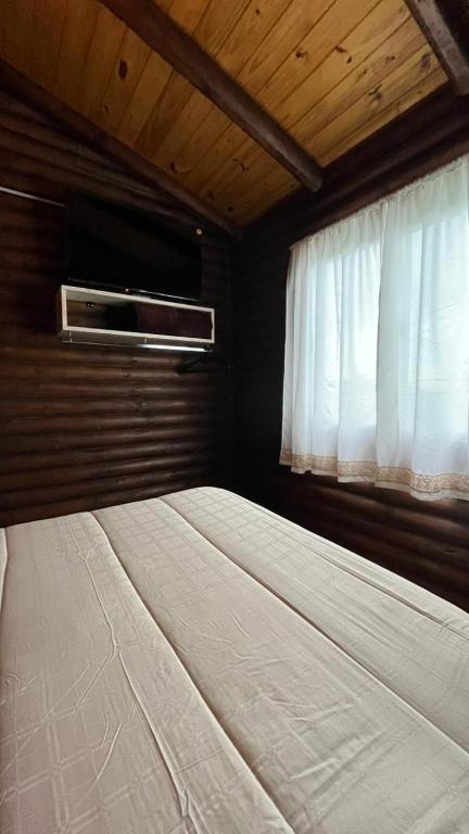 a bedroom with a large bed with a window at Cabañas La Silvanita in Balcarce