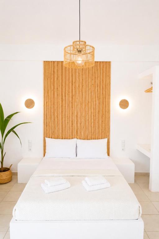 a bedroom with a white bed with a wooden headboard at Elichri Theros Studios in Katelios