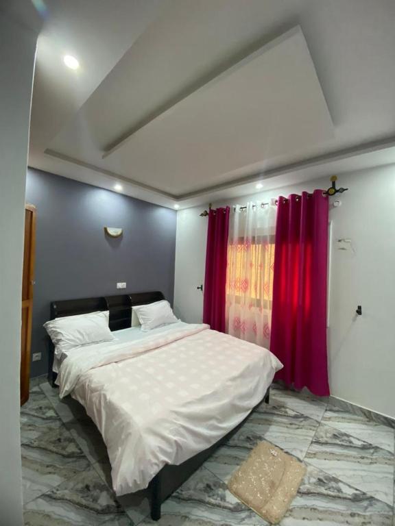 a bedroom with a large bed with red curtains at Lita résidence in Yaoundé