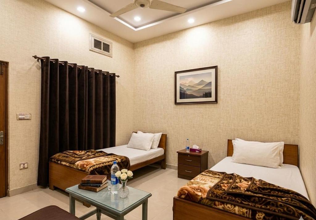 a hotel room with two beds and a table at Al Hidayah Hotel Multan in Multan