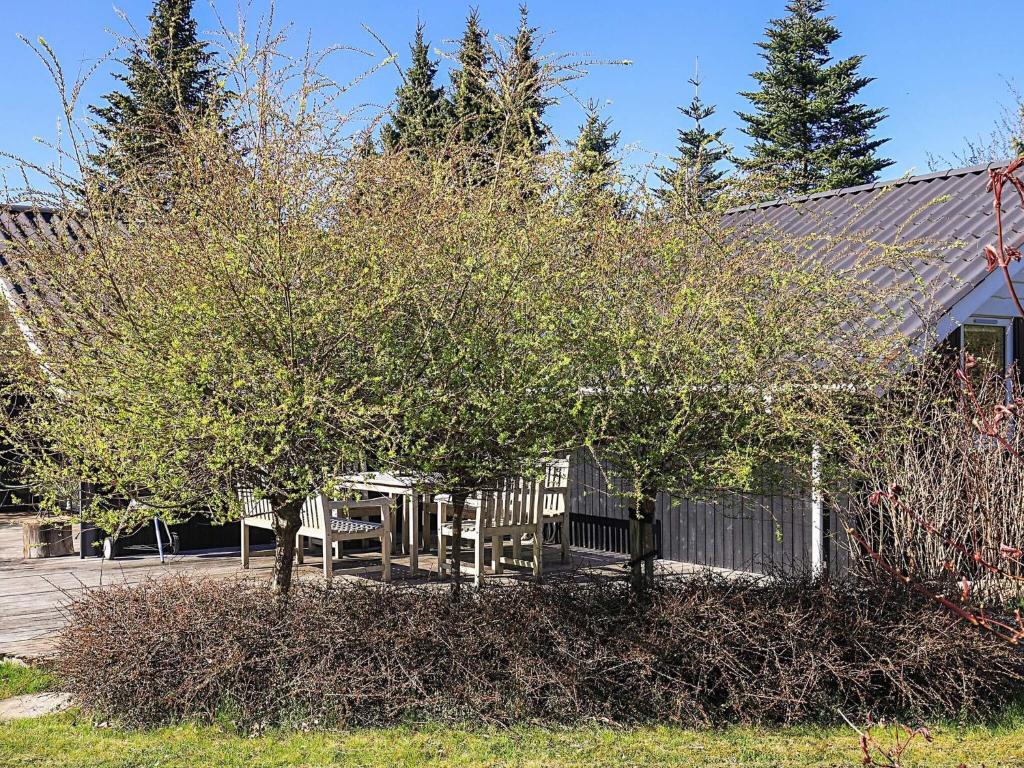 a table and chairs under a tree next to a house at 4 star holiday home in Græsted in Græsted