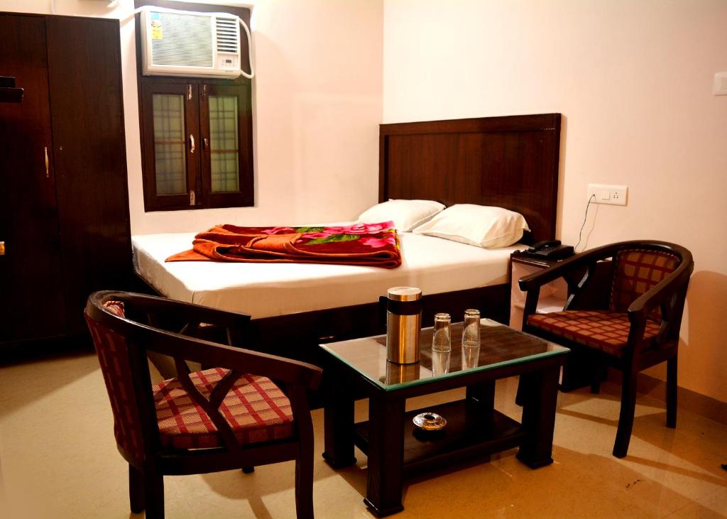 a bedroom with a bed and two chairs and a table at Hotel Thakur Ji in Haridwār