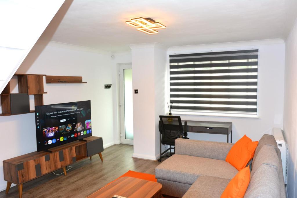 a living room with a couch and a flat screen tv at Magic House- London in Plumstead