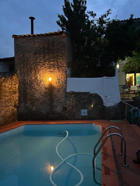 a swimming pool in front of a stone wall at Casa dos Cândidos in Alagoa