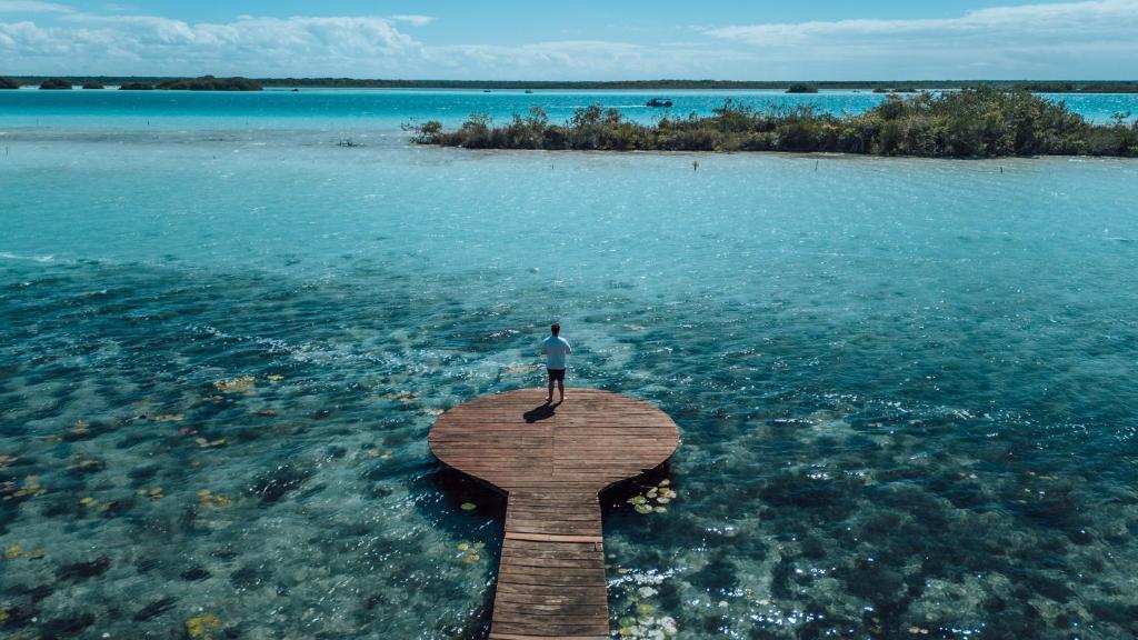 a person standing on a pier in the water at Hotel CasaBakal - A pie de Laguna - Bacalar in Bacalar