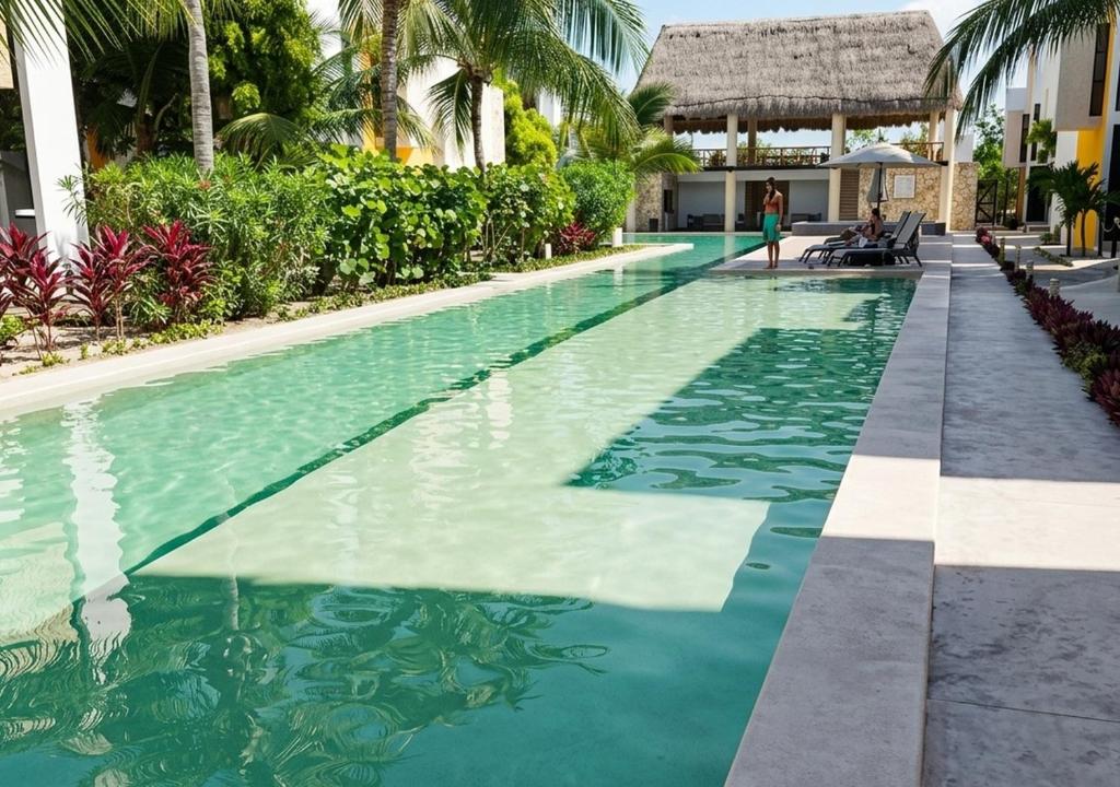 a swimming pool at a resort with palm trees at Telchac 3 bedrooms, pool and beach in Telchac Puerto