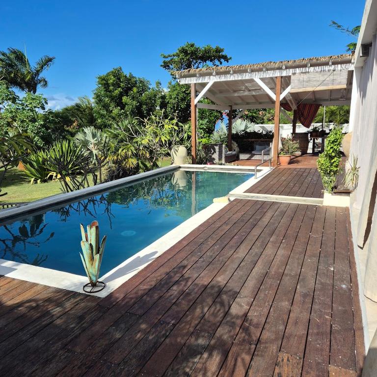 a swimming pool with a wooden deck next to a house at Villa Rose Barth Location de Chambre in Saint-Louis