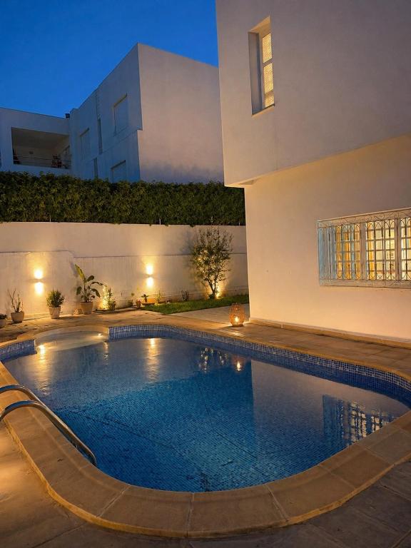 a swimming pool in front of a house at night at Villa Marsa in Dar el Haj Ahmed Souid