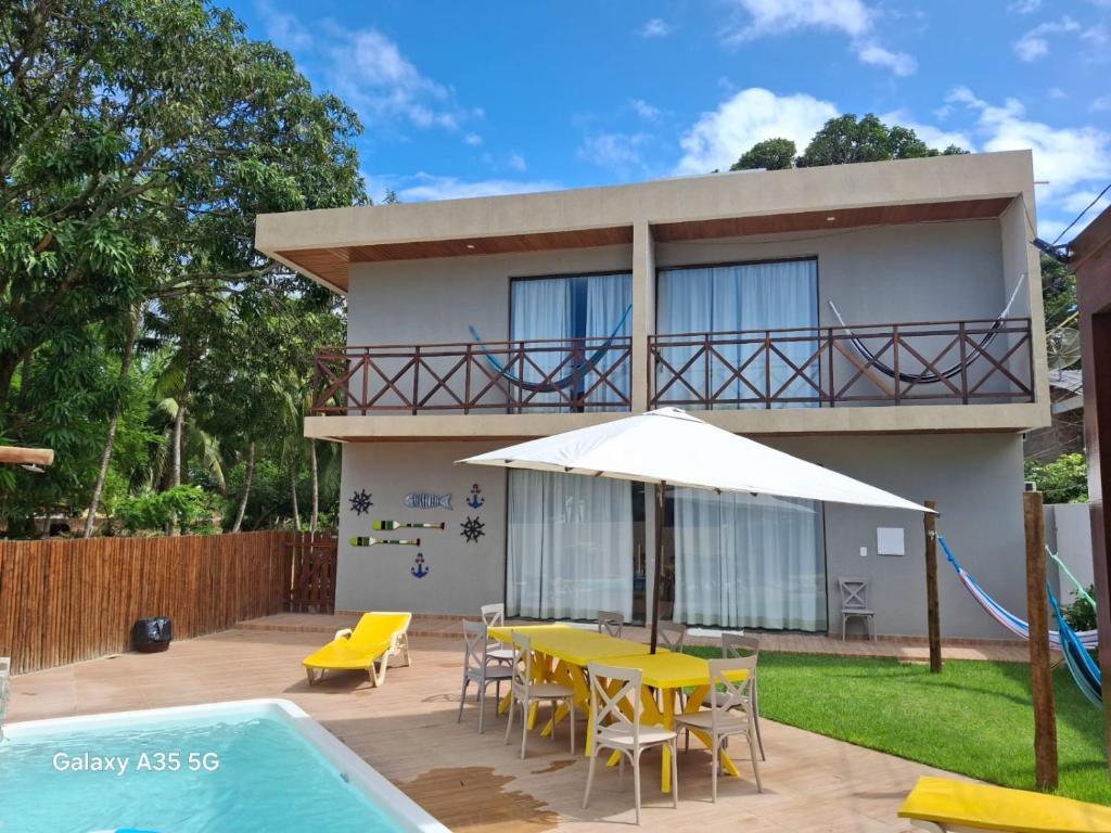 a house with a table and chairs and an umbrella at Antunes Beach Flats Paradise in Maragogi