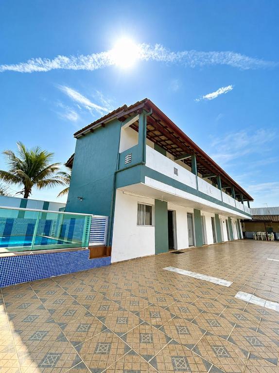a blue and white building with a tile courtyard at Recanto dos Amigos Suítes CANTÃO DO INDAIA in Bertioga