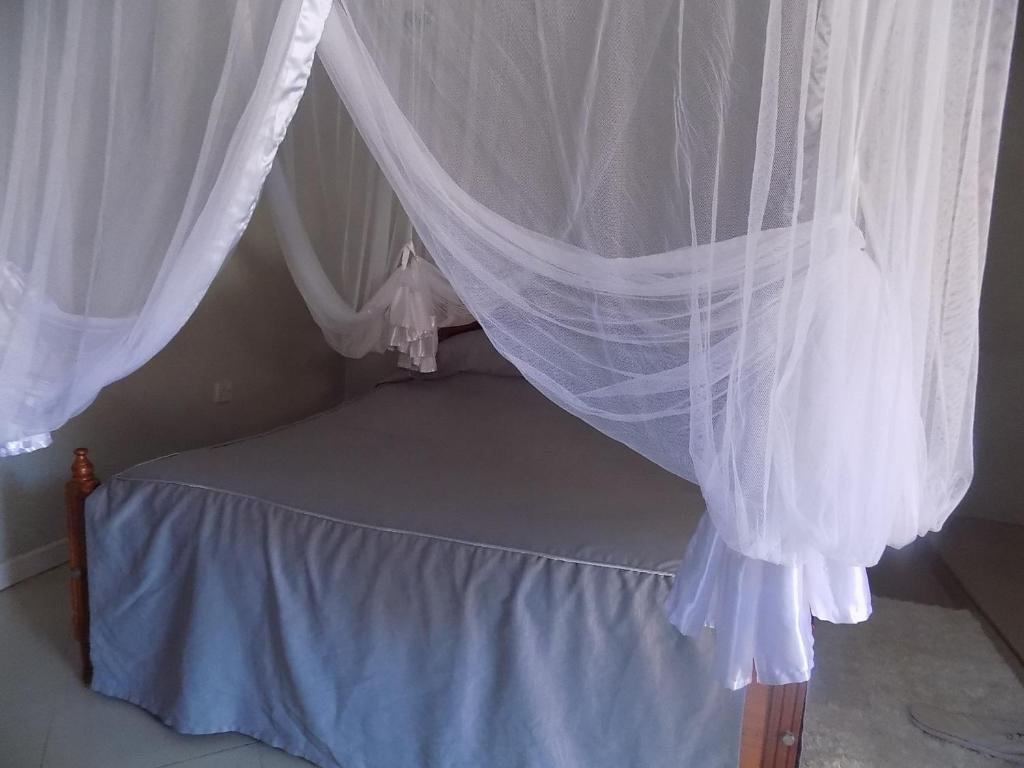 uma cama de dossel com cortinas brancas em Lubowa Cottages em Bukusu