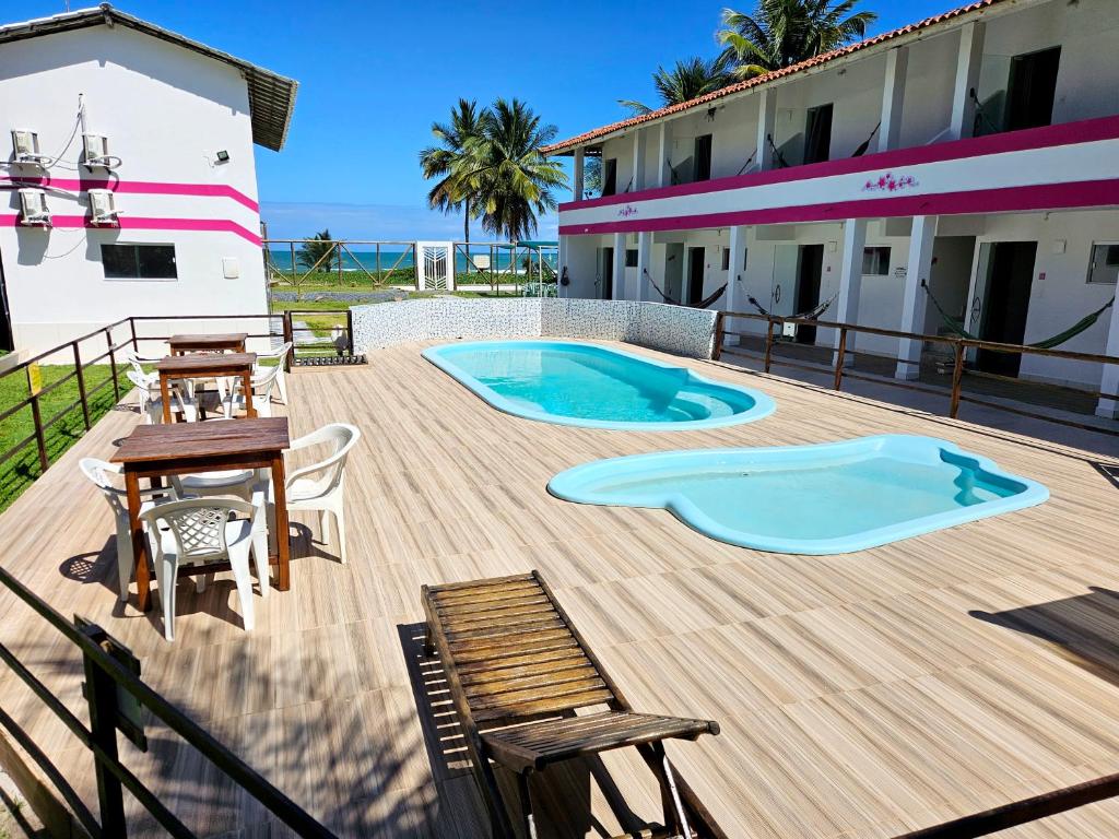 a deck with a pool and a table and chairs at Pousada Sol Nascente in Guaibim