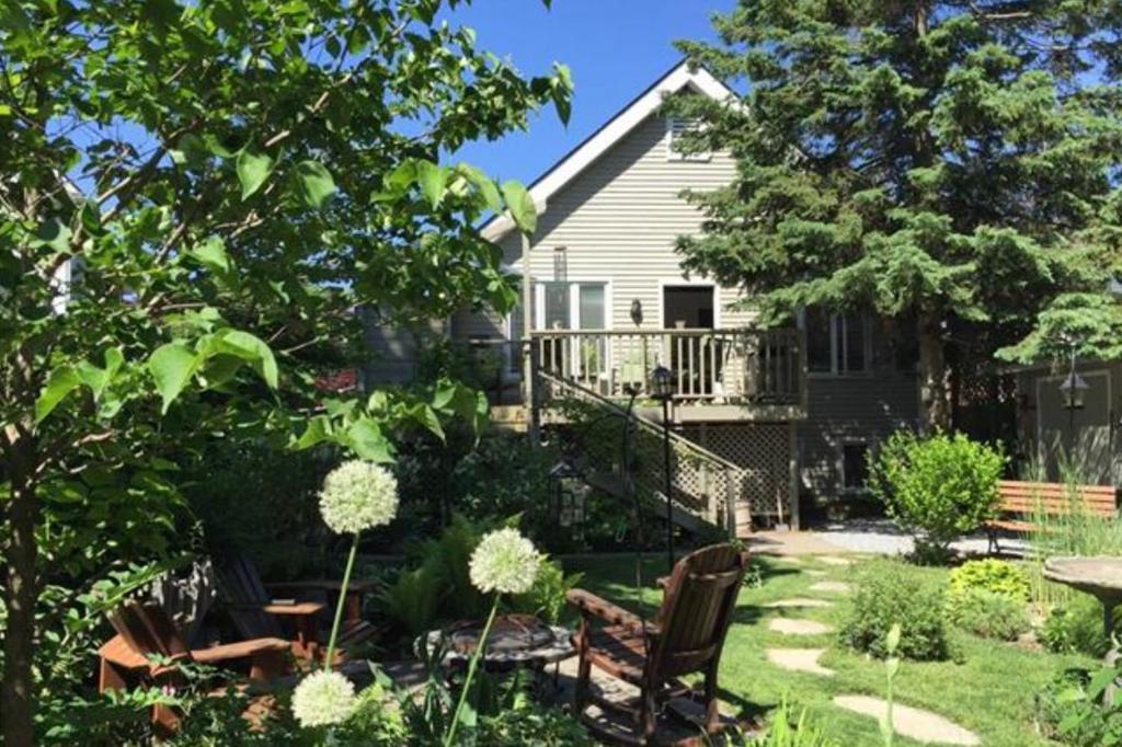 een huis met een tuin met stoelen en een patio bij 2 Moon Cottage in Niagara on the Lake