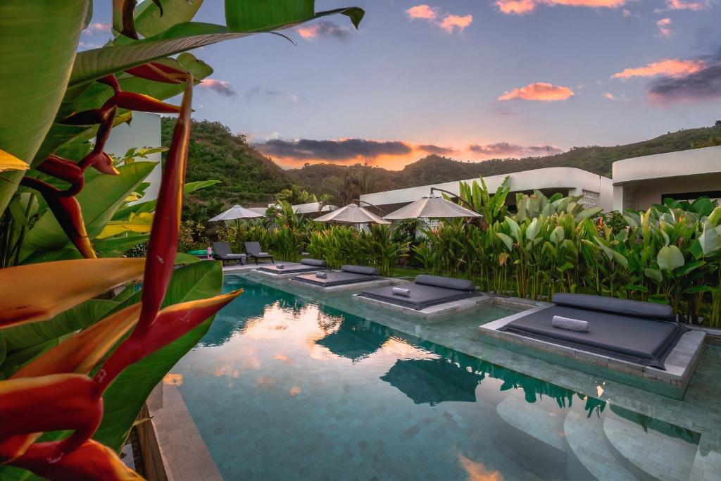 a pool at a resort with a sunset in the background at Amazing Lombok Resort in Selong Belanak