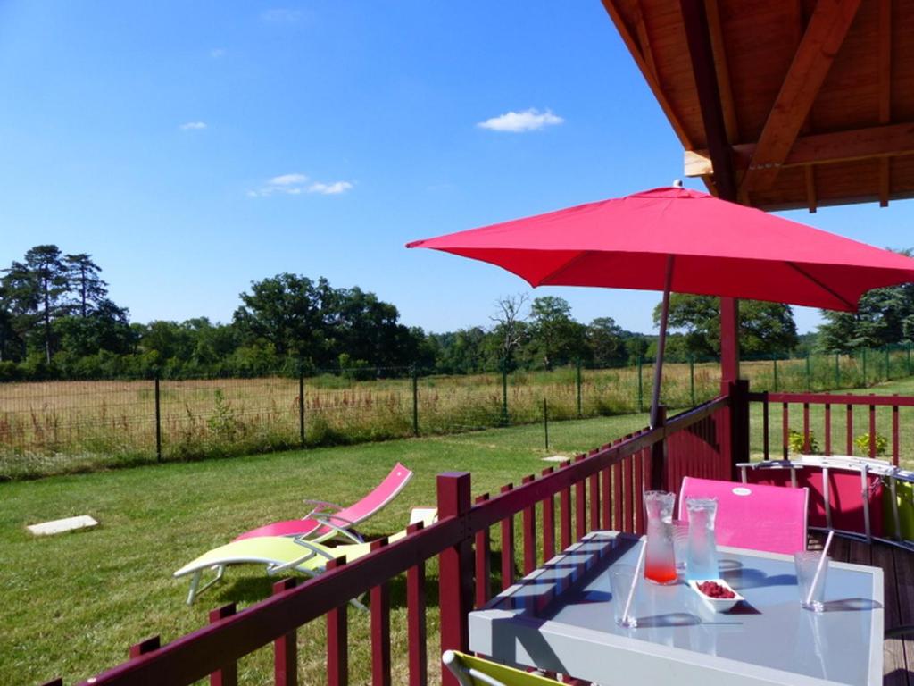 a table with a red umbrella and chairs on a deck at Gîte cozy avec terrasse et climatisation près de Saint Pourçain - FR-1-489-267 in Meillard