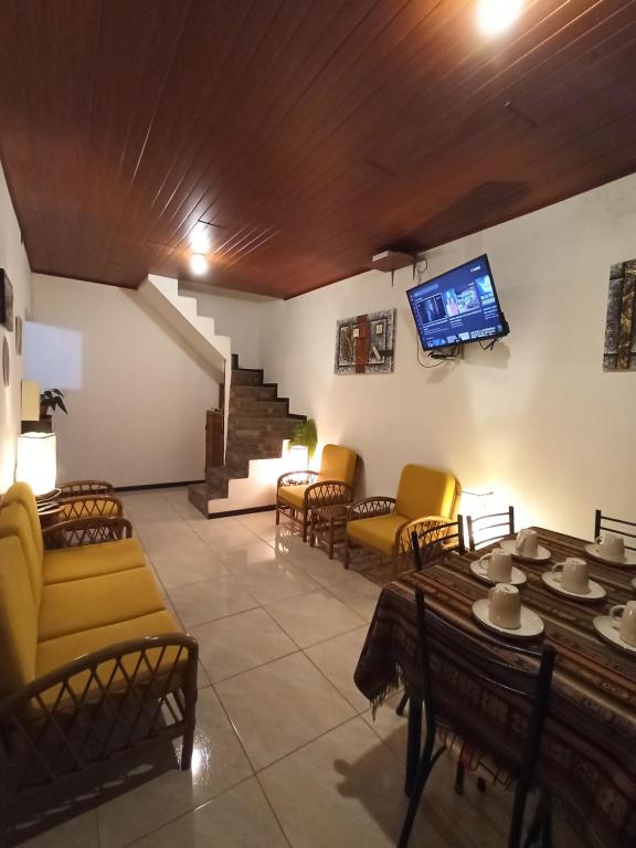 a living room with chairs and a tv on the wall at Home Capybara Stay in Mindo