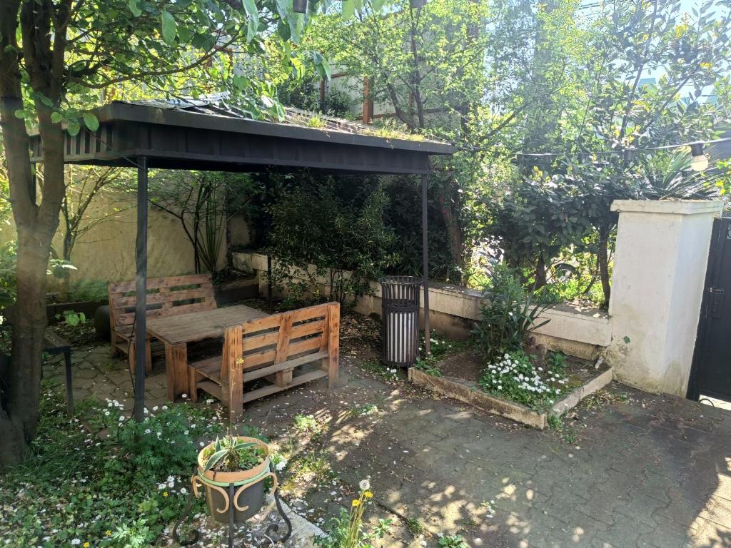 a wooden bench under a gazebo in a garden at Happy house in Kobuleti