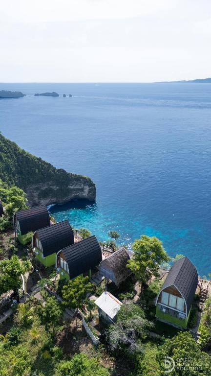 a group of huts on a hill next to the water at Eco-tourist Dream Beach Cliff Villas in Nusa Penida