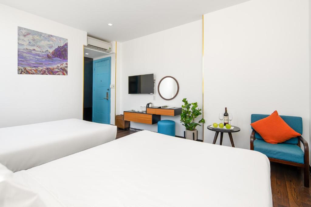 A twin-bed room with a colourful chair, fruit table and wall-mounted television.