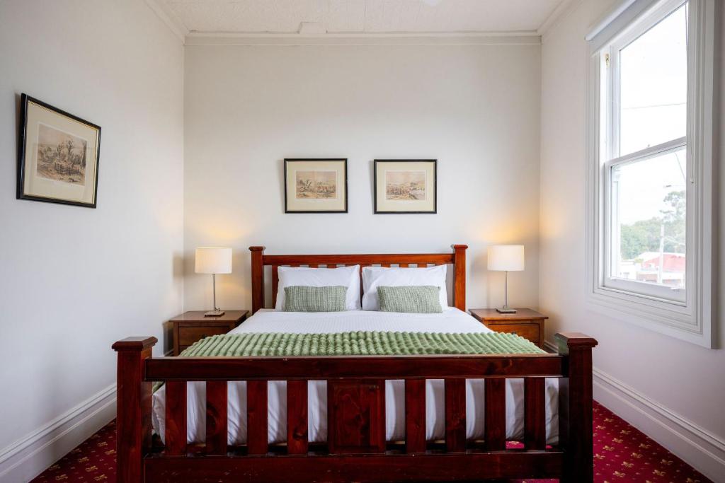 a bedroom with a wooden bed and two windows at The Corner Hotel Alexandra in Alexandra