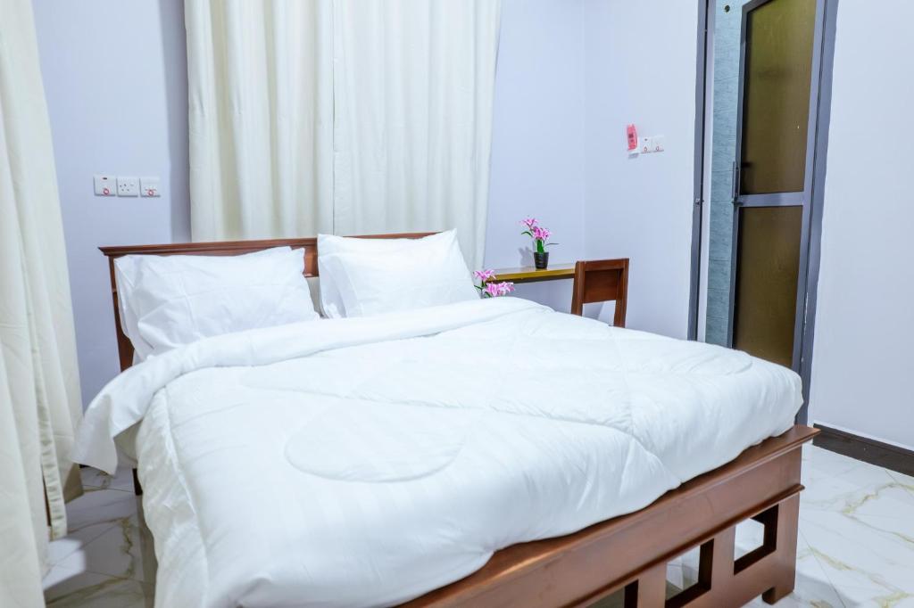 a bedroom with a bed with white sheets and pillows at Cozycore Apartment in Dodoma