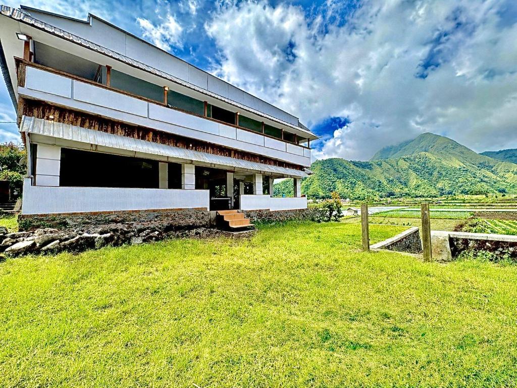 a building in a field with mountains in the background at Nara Hills in Sembalun Lawang