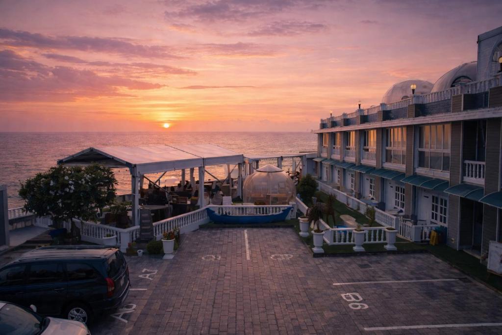 a building with a parking lot next to the ocean at State Beach Resort And Spa in Kannur
