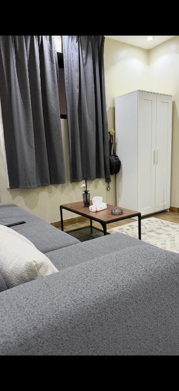 a bedroom with two beds and a table and curtains at شقق تاج اليرموك الفندقية in Tabuk