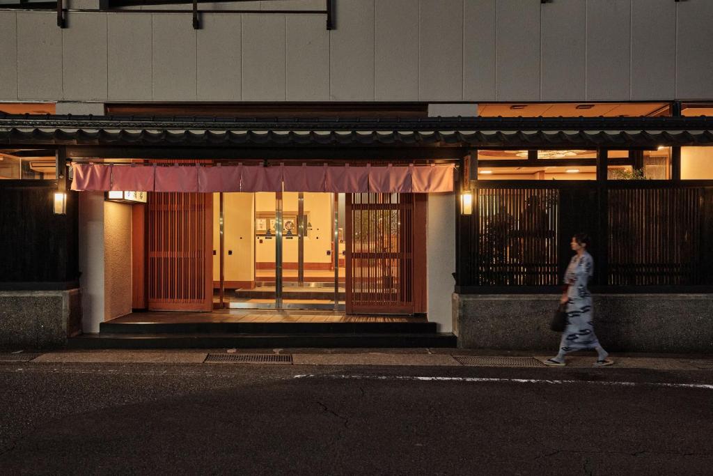 a woman walking down a street in front of a building at Manseiro in Nachikatsuura