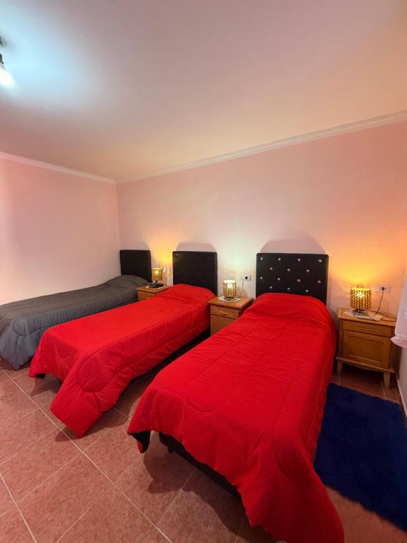 two beds in a room with red sheets at Duna Blanca I in Fiambalá