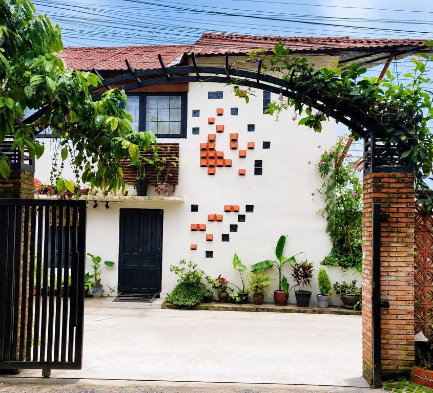 a white house with an arch with plants on it at roc rach homestay in Ấp Tân Hà