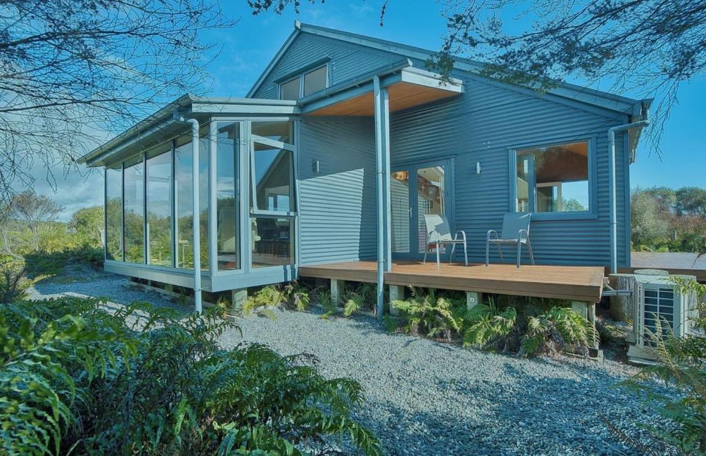 a blue house with a porch and a deck at Fern View - Cozy 2-bedroom house in Hokitika