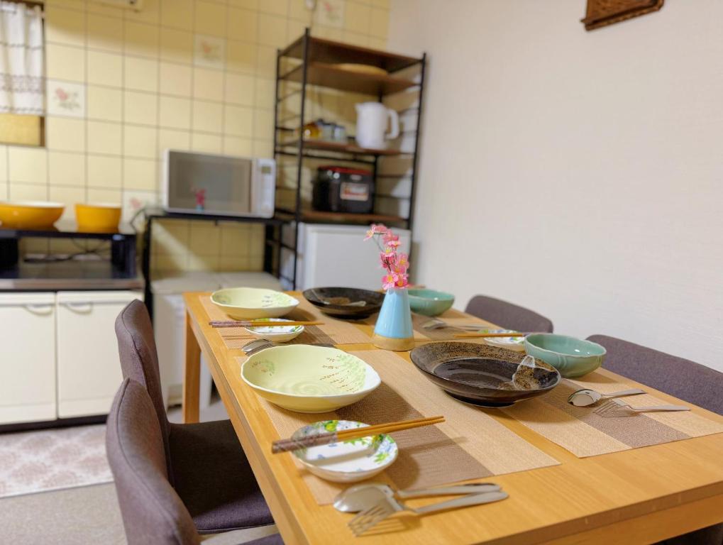 a wooden table with bowls and plates on it at Ema-長吉 in Osaka