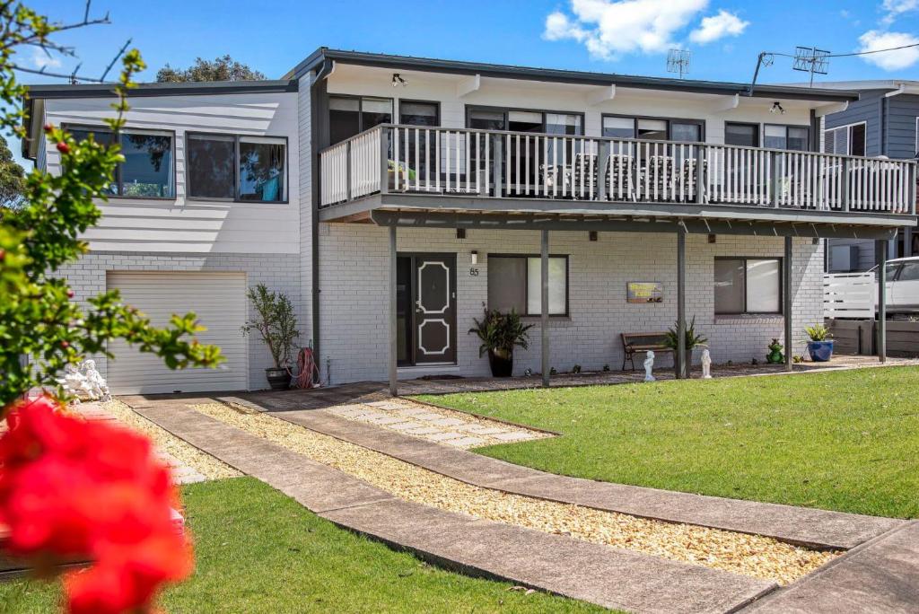 a house with a balcony and a yard at Mollymook Beach Haven - near ocean & golf course in Mollymook