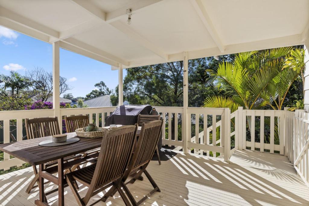 a porch with a wooden table and chairs at Jillby's House - 3 BR home near Narrawallee Beach in Narrawallee