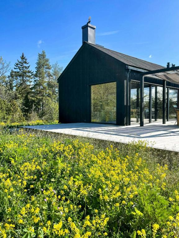 a black building with windows and a field of yellow flowers at Architect-Designed House In Etelhem, Gotland in Stånga