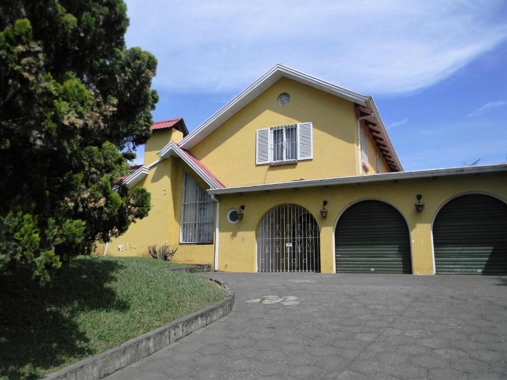 ein gelbes Haus mit zwei Garagentüren und einer Einfahrt in der Unterkunft Habitacion Santo Domingo, Heredia in Santo Domingo