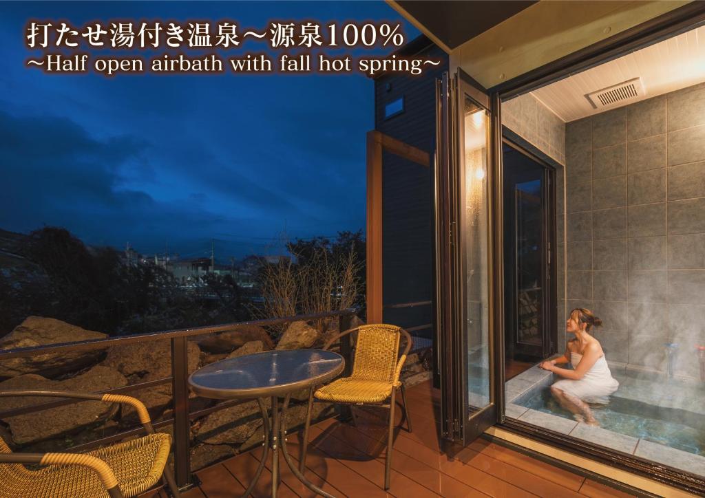 a woman sitting in a hot tub on the balcony of a house at 湯宿 蒼の月 in Oita