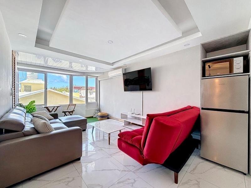 a living room with a couch and a red chair at Les Sables Roses Appartement in Flic-en-Flac