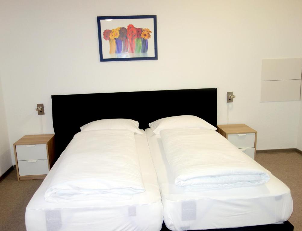 a large bed with white sheets and two night stands at Budget Hotel Ludwigshafen in Ludwigshafen am Rhein