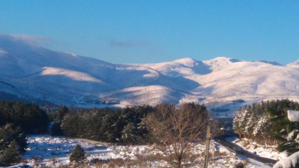 a snowy mountain range with trees and snow covered mountains at Casa Rural La Vereilla in Barajas de Gredos