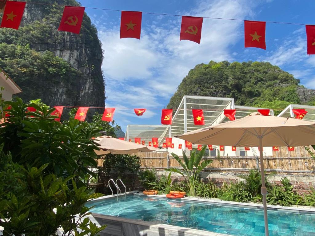 a resort with flags and a pool with a mountain in the background at Tam Coc Harmony Homestay in Vũ Lâm