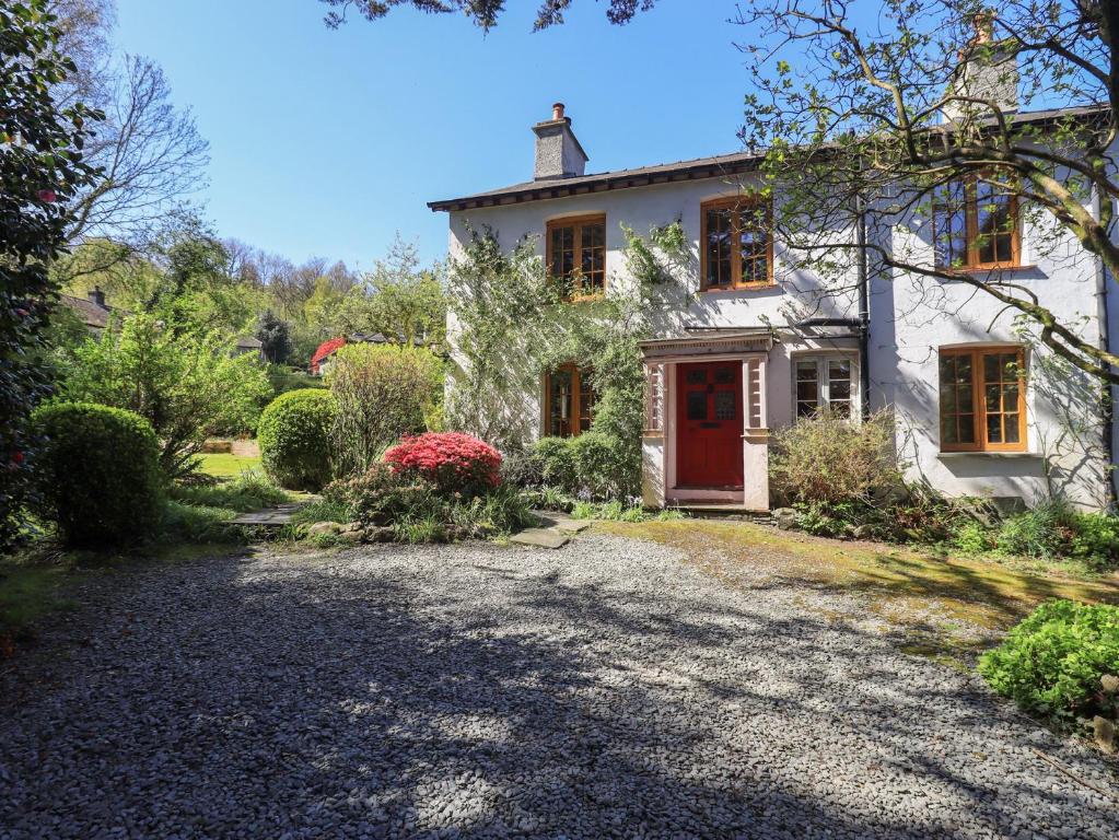 a white house with a red door and a driveway at Rose Cottage Coniston in Coniston