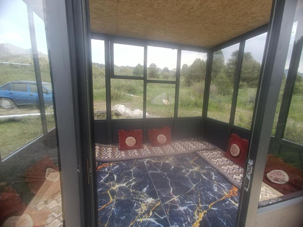a screened in porch with red pillows in front of a window at Archa in Osh