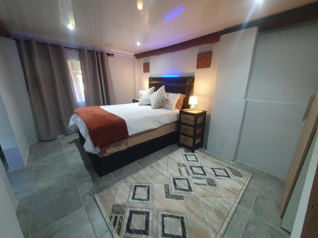 a bedroom with a bed and a lamp on a table at Blu light lodge in Randfontein