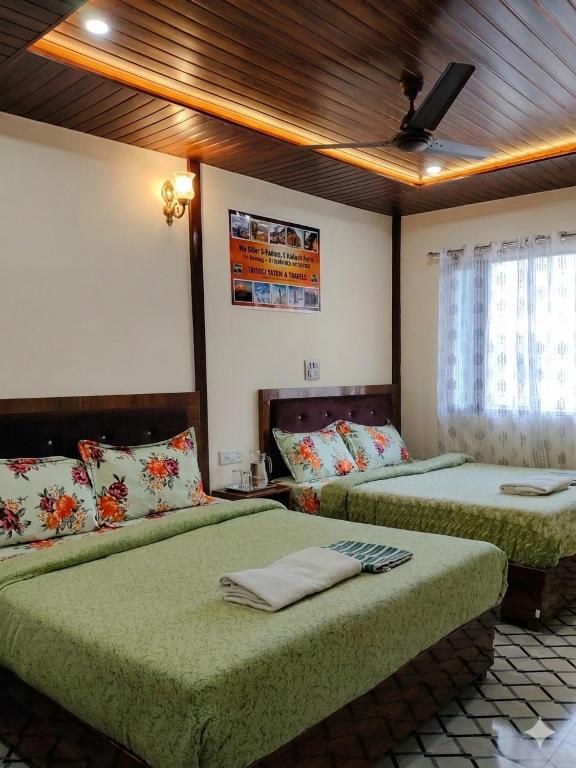 a bedroom with two beds and a ceiling at Trinetra Himalayan Stay in Phata