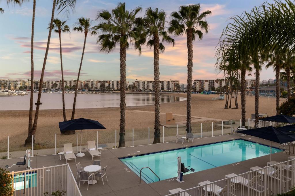a swimming pool with palm trees and a beach at Jamaica Bay Inn Marina Del Rey Tapestry Collection by Hilton in Los Angeles