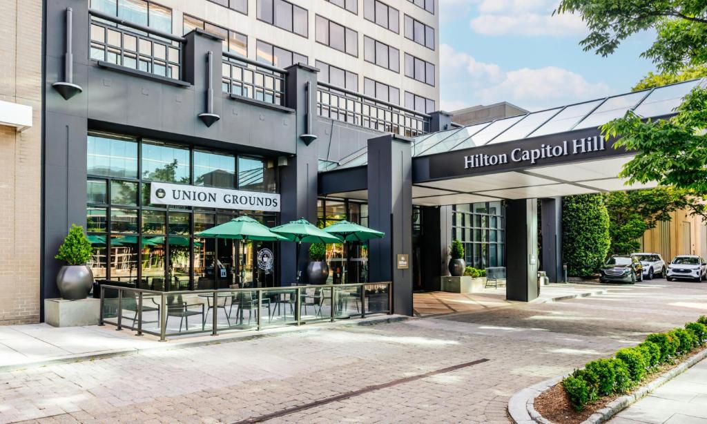 a building with tables and umbrellas in front of it at Hilton Washington DC Capitol Hill in Washington, D.C.