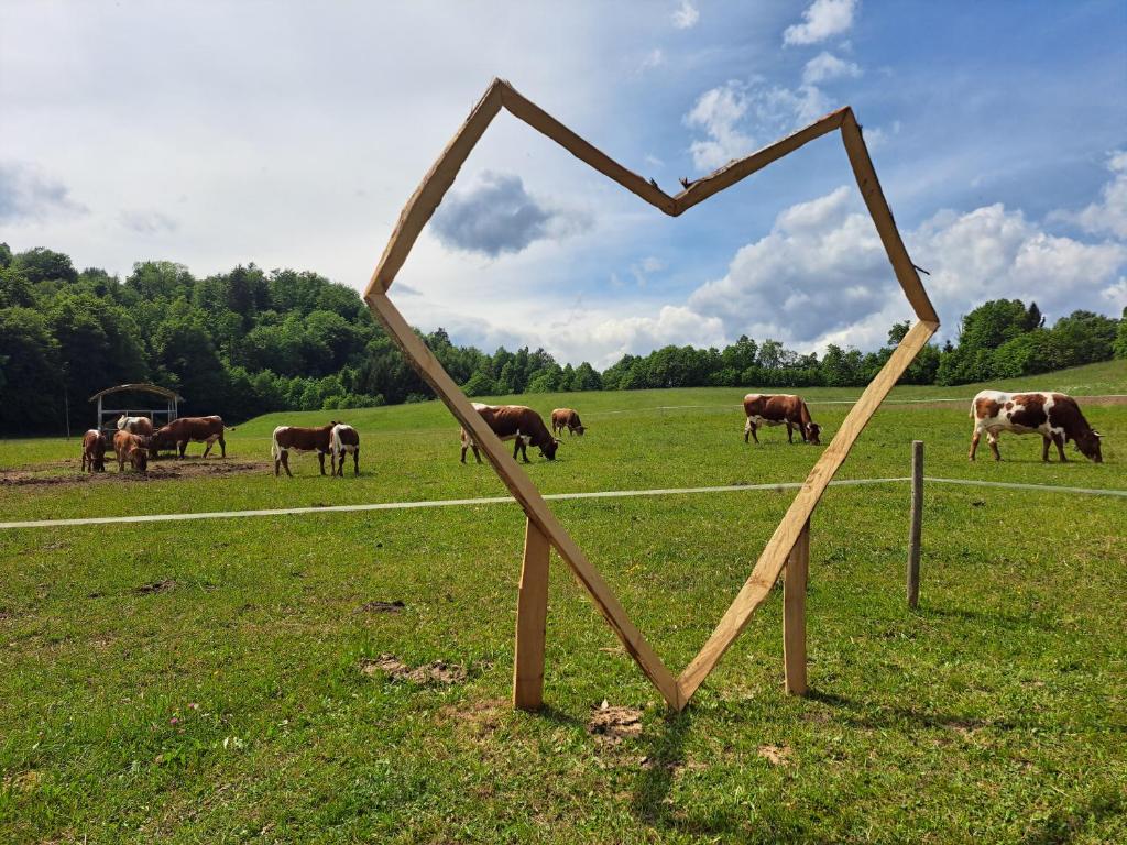a wooden heart in a field with cows grazing at PUŽMAN Farm Glamping in Radovljica